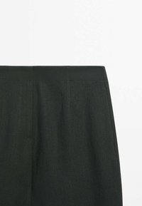 Dark green trousers with a smooth, textured finish, featuring a flat waistband and subtle stitching details. No visible hardware or patterns.