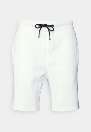 Hvite sweatshorts laget av bomull, med en svart snor i det elastiske midjebåndet og lommer på siden. Glatt tekstur og lengde til midt på låret.