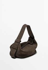 Brown suede shoulder bag with a soft, curved shape, featuring a wide strap secured by a buckle, and subtle stitching accents.