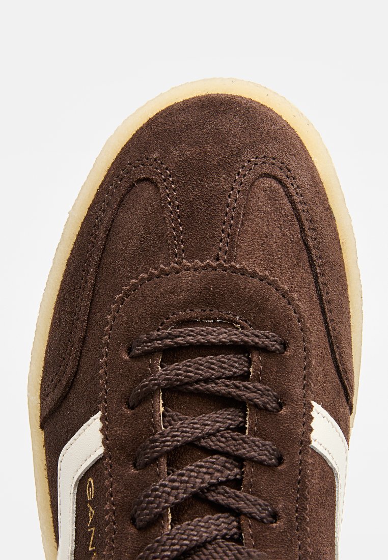 Baskets en suède marron avec des accents en cuir blanc, bout rond et semelle en caoutchouc contrastante. Comprend des lacets épais et des détails cousus.