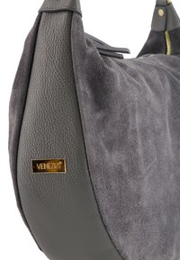 Gray handbag featuring a combination of textured suede and smooth leather, with a gold logo accent and zip closure.