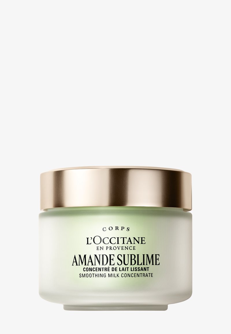 Concentré lissant au lait d'amande L’OCCITANE dans un pot en verre dépoli avec un couvercle doré sur fond blanc.