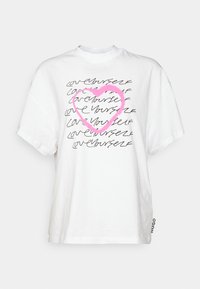 Hvid bomulds t-shirt med korte ærmer, der har et trykt design af "elsk dig selv" i sort og et hjerte med pink omrids. Mærkeetiket på siden.