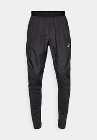 Pantalons de sport noirs avec une finition mate, taille élastique, poches latérales et jambe fuselée. Présente un logo sur la hanche gauche.