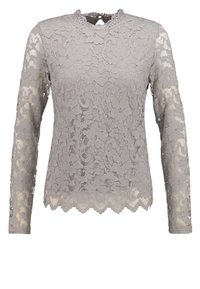 Blonder langærmet top i lys grå. Har bølgede kanter og et blomsterpatter. Nøgnehalssnit. Gennemsigtig tekstur.