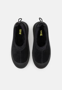 Black slip-on shoes made of soft suede, featuring a padded collar, elasticized opening, and textured rubber sole. Lined interior for comfort.