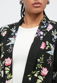Fekete, virágmintás blézer élénk rózsaszín és kék virágmintákkal, puha anyagból, bevágott gallérral és nyitott elülső résszel.