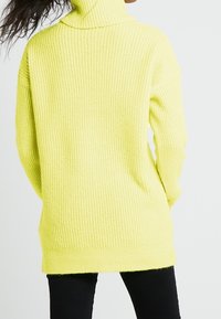 Pitkähiha, merinovillainen tikkikuvioinen neule paksussa ribbineuloksessa, jossa on löysä ja ylipitkä malli.