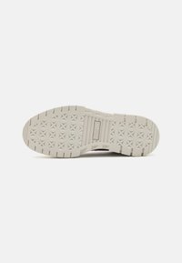 Schuh mit einer strukturierten Gummisohle mit Sternen-Muster, in hellgrauer Farbe mit gerippten Kanten, mit dem Logo 'Puma' in der Mitte.