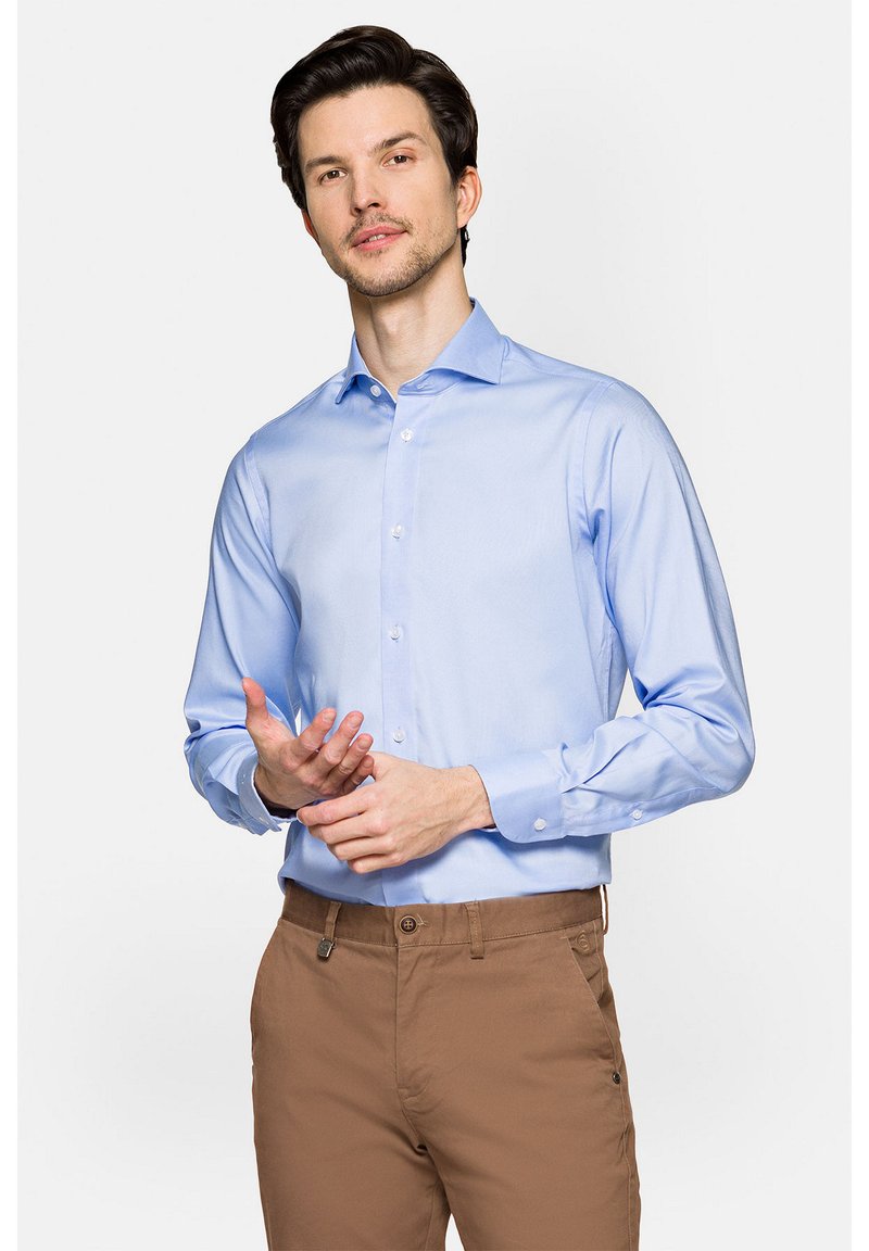 Jasnoniebieska koszula z długim rękawem i spiczastym kołnierzykiem, o gładkiej fakturze i zapięciach na guziki, w połączeniu z brązowymi spodniami.