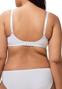 Reggiseno bianco con spalline regolabili, texture liscia e chiusura a gancio sul retro. Presenta un design senza cuciture per il massimo comfort.