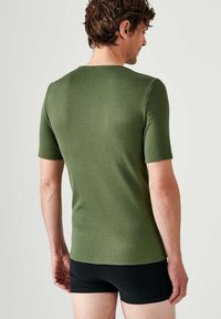 T-shirt a maniche corte di colore verde oliva con un design aderente, realizzato in un tessuto liscio e elasticizzato. Nessun motivo visibile o dettagli metallici.
