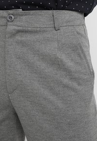 Gråbyxor med en melerad textur, framknappstängning och sidofickor, med en slät tygfinish och skräddarsydd passform.