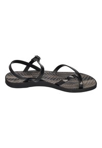 Black flat sandals with thin, glossy straps. Textured gray outsole features a herringbone pattern. Adjustable buckle on the ankle strap.