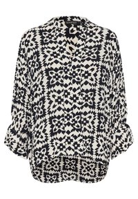 Sort-hvid mønstret skjorte med V-hals, rullede ærmer og en asymmetrisk kant. Stoffet har geometriske designs.