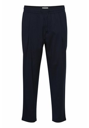 Marineblauwe op maat gemaakte broek met een trekkoord in de taille, geplooide voorkant en taps toelopende enkels. Gemaakt van een gladde, lichte stof.