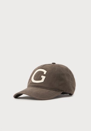 Casquette de baseball marron avec une lettre blanche G sur le devant et une visière incurvée sur un fond uni.