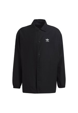 Fekete gombos dzseki sima textúrájú anyagból. Gallérral, hosszú ujjal rendelkezik, és a bal mellen egy kis fehér Adidas-logó található.