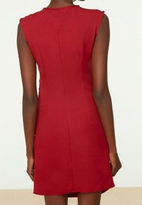 Rode mouwloze jurk met een strakke pasvorm, een gladde textuur en een knielange snit, met een subtiele gradient aan de zoom en detail aan de achternaad.
