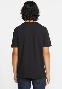 Sort kortærmet t-shirt med rund hals, fremstillet af blødt bomuld. Viser et enkelt design uden synlige logoer eller mønstre.