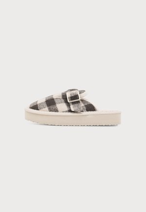 Slip-on hjemmesko med sort- og hvidternet stof, sølvspænde og tyk beige sål på ensfarvet baggrund.