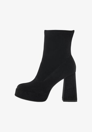 Bottines noires en daim souple avec un haut talon bloc et une plateforme. Présente un design épuré avec des détails de coutures minimaux.