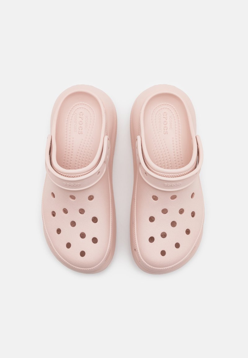 Zuecos rosa claro hechos de plástico flexible, con un diseño perforado, correa trasera ajustable y plantillas texturizadas para mayor comodidad.