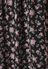 Tissu noir avec un motif floral répétitif composé de petites roses roses et de feuilles vertes, créant une apparence délicate et texturée.