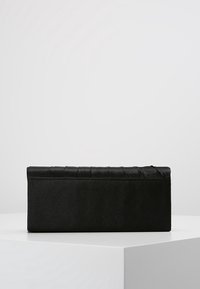 Sac à main rectangulaire noir en satin avec un design matelassé. Présente des coutures subtiles le long des bords et une surface lisse et élégante.