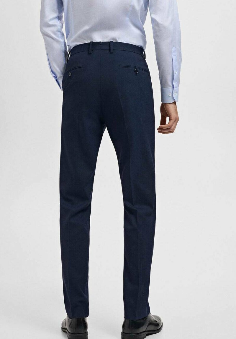 Navyblaue maßgeschneiderte Hose mit geradem Schnitt, Gesäßtaschen und feiner Textur. Getragen mit einem hellblauen Hemd mit Kragen und schwarzen Schuhen.