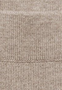 Vaalea beige neuloskangas, jossa on tekstuuri ja ribbikuvio. Pehmeä ja paksu, esittelee saumattoman muotoilun, jossa on hienovaraisia värivariaatioita.