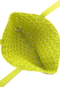 Jasnożółta plastikowa torba o kształcie kwadratu. Posiada skomplikowaną plecioną teksturę i solidne płaskie ramiączka. Otwarty górny brzeg odsłania przestronne wnętrze.