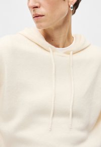 Κρέμα φούτερ φτιαγμένο από μαλακό ύφασμα, με κορδόνι στον λαιμό, άνετη εφαρμογή και ribbed λεπτομέρειες στο στρίφωμα.