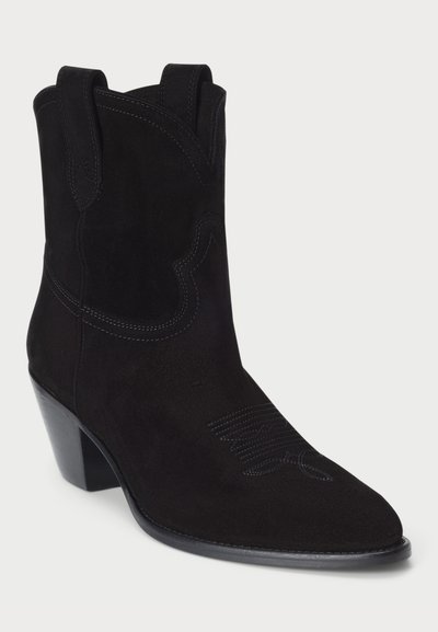 Botte de cowboy en daim noir avec un bout pointu, un talon empilé, une tige courbée et des coutures ton sur ton comportant des détails décoratifs sur la partie supérieure.