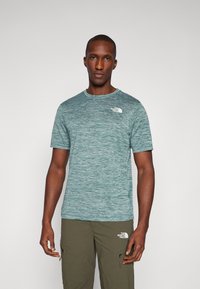 Lühikeste varrukatega spordisärk teallasest melange kangast, ümmargune kaelus, vasakul rinnal valge logo, koos oliiviroheliste cargo-pükstega.