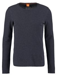 Pull en maille bleu foncé à manches longues avec col rond et petite étiquette de marque près de l'ourlet sur fond blanc uni.