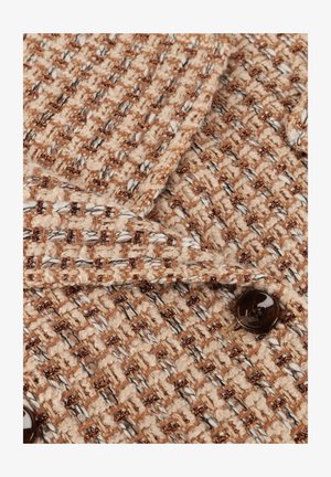 Tissu tissé beige et marron avec des accents en fil métallique. Présente une surface texturée et un détail de bouton marron foncé.