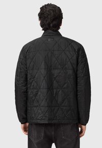 Czarna pikowana kurtka z fakturowaną powierzchnią w diamentowe wzory. Posiada klasyczny kołnierz oraz metkę z tyłu szyi.