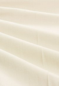 Tissu crème clair avec un tissage lisse et texturé. Affiche de douces plis et une apparence douce, adaptée à diverses applications textiles.