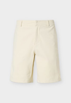 Krémově bílé elegantní krátké kalhoty ke kolenům s poutky na pásek a zapínáním vpředu, zobrazené na jednoduchém bílém pozadí.