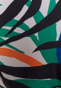 Tecido multicolorido com um padrão de formas de folhas abstratas em preto, verde, laranja e azul sobre um fundo claro. Textura suave.