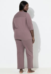 Pohovková souprava z jemné mauve tkaniny, s krajkovaným vzorem na zádech a krajkovým lemem na spodní části. Tříčtvrteční rukávy, kalhoty rovného střihu.