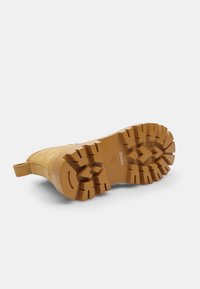 Botte marron à semelle en caoutchouc avec une surface texturée, dotée d'une languette et d'une semelle crantée pour l'adhérence. Tige en cuir souple.