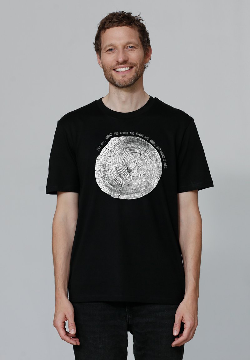 Zwart T-shirt met een zilveren boomring graphic in het midden. Korte mouwen, ronde halslijn, zachte stof en een relaxte pasvorm.