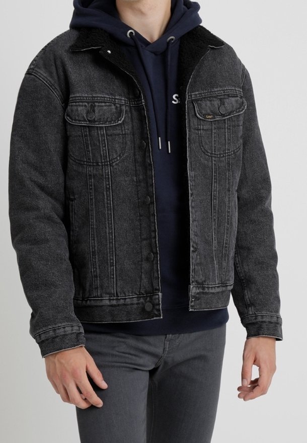 Black denim jacket with a sherpa collar, featuring buttoned front pockets, slight fading, and a classic fit. Worn over a navy hoodie.