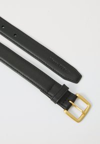Zwarte leren riem met een gladde textuur, voorzien van een gouden rechthoekige gesp en verschillende verstelgaten. Getextureerd merklogo op de band.