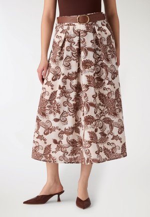 Gonna midi con motivo floreale paisley marrone, pieghe frontali, cintura marrone, abbinata a mule marroni con tacco e punta appuntita indossate da una modella.