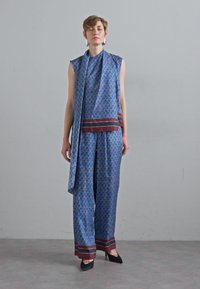 Blau gemustertes Zweiteiler-Outfit mit ärmellosem Top und lockeren Hosen. Verfügt über kastanienbraune horizontale Streifen an der Taille und am Saum. Glatter Stoff, elegantes Design.
