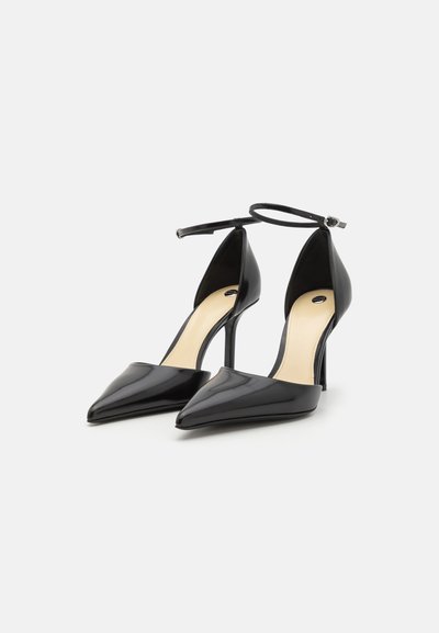 Pantofi cu toc înalt din piele patent neagră, cu vârf ascuțit, brățară la glezna și un finisaj elegant, neted. Culoare solidă, accente minime.