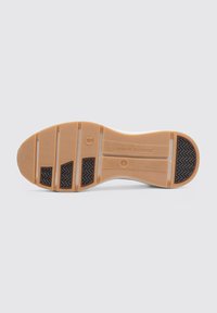 Suela de zapato de caucho beige con un patrón texturizado. Presenta crestas para un mejor agarre, un logo en el centro y una sección lisa cerca del talón.